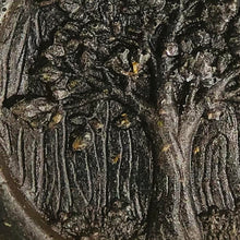 Charger l&#39;image dans la galerie, An extreme close-up view of grey face soap with an embossed tree design, and embedded black specks of charcoal and small, brown pieces of hemp that can be seen.
