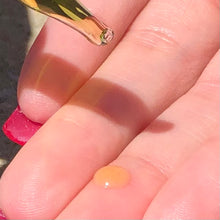 Load image into Gallery viewer, Closeup of a glass dropper and a drop of golden oil on a middle finger.

